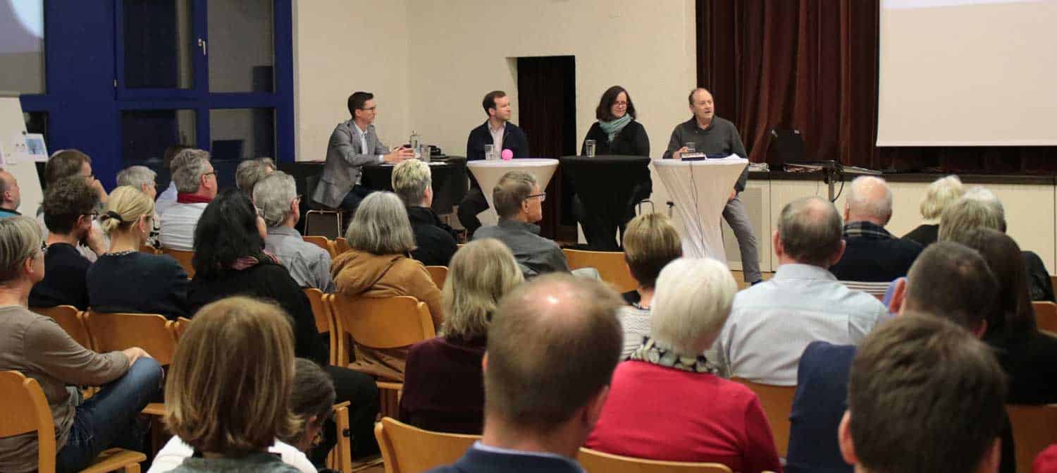 Zahlreiche interessierte Besucherinnen und Besucher hören den spannenden Diskussionen zu.