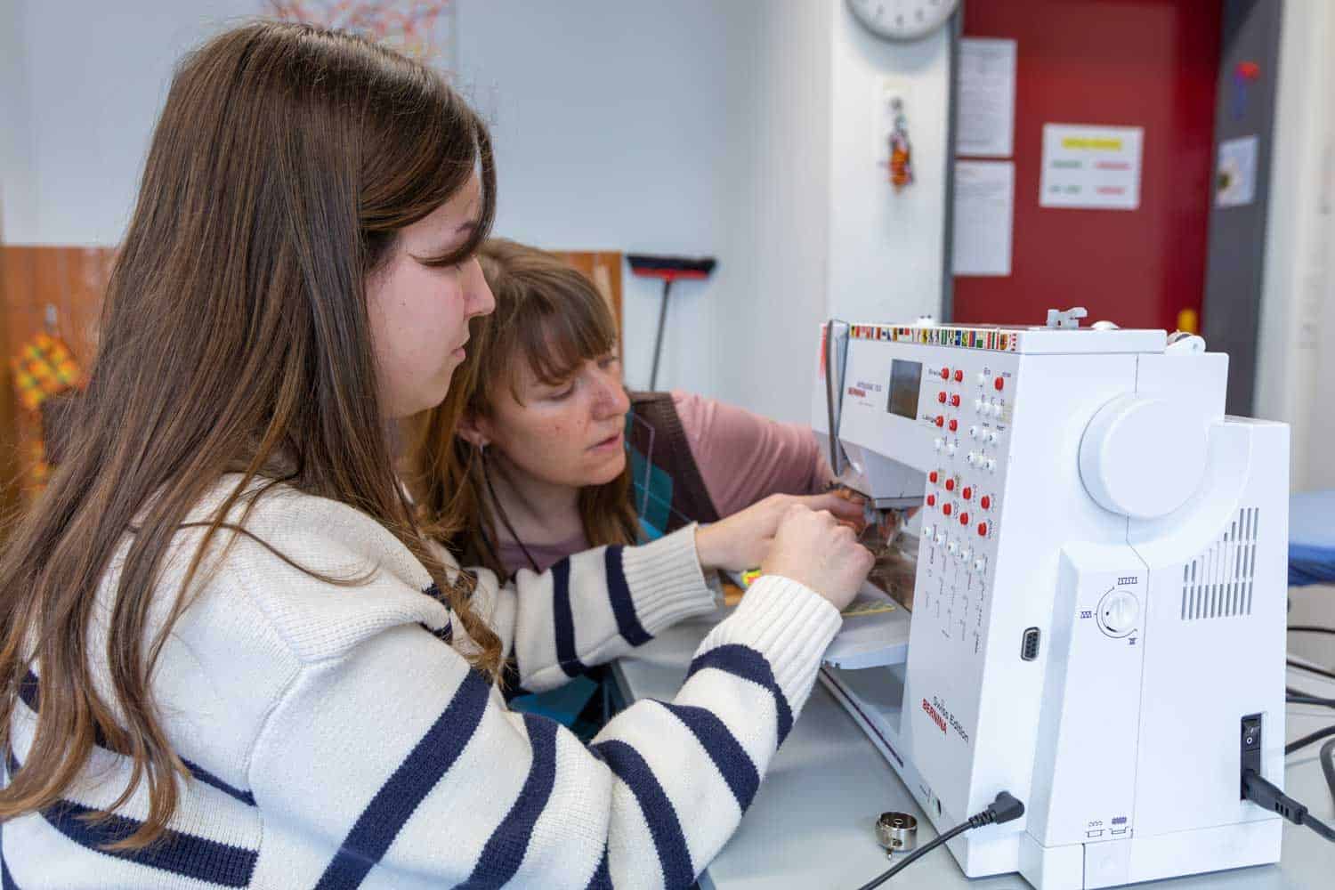Sehbeeinträchtigte Jugendliche bedient mit Hilfe einer Therapeutin eine Nähmaschine. Sehbeeinträchtigte Jugendliche bedient mit Hilfe einer Therapeutin eine Nähmaschine.