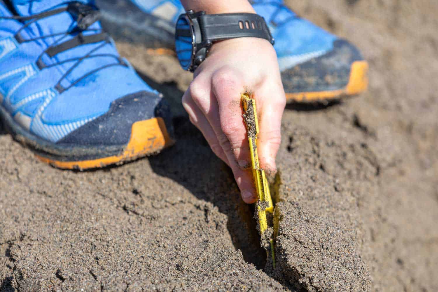 Person gestaltet Abgrenzungen im Sandkasten, symbolisch für die sichere und individuelle Arbeitsumgebung.