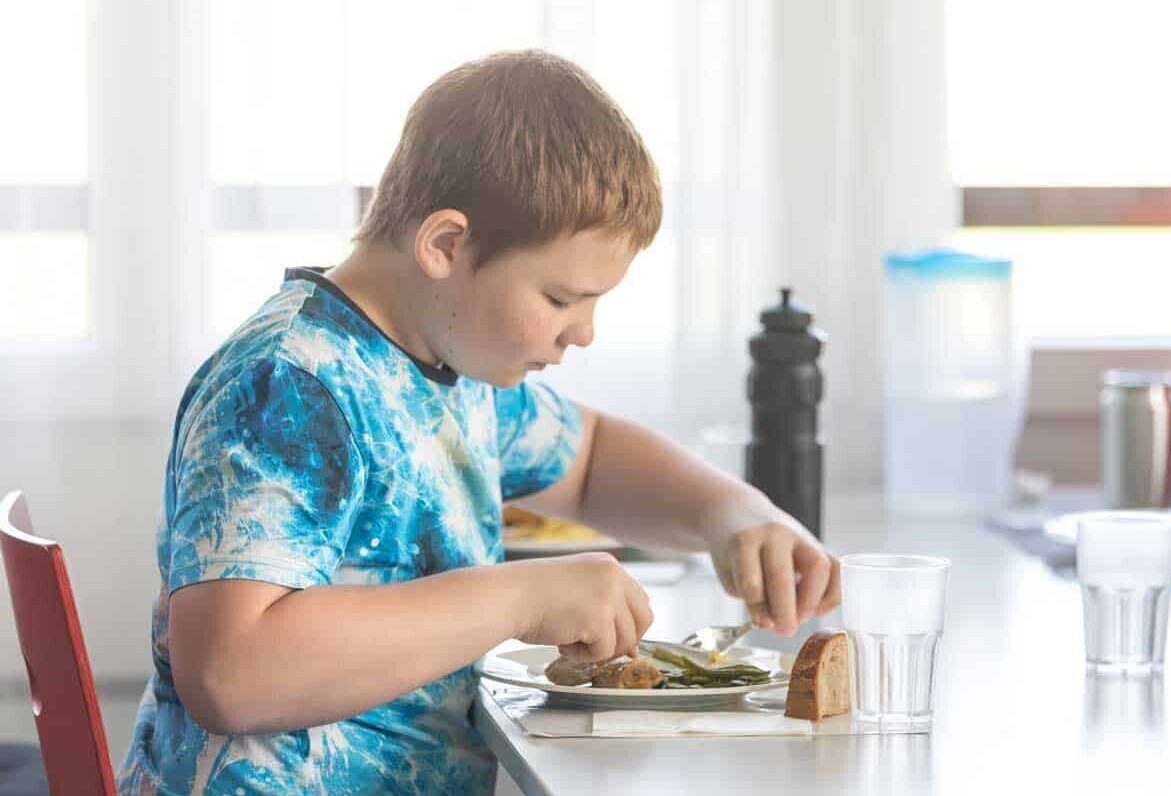 Jugendliche sitzen gemeinsam am Tisch und essen zu Mittag.
