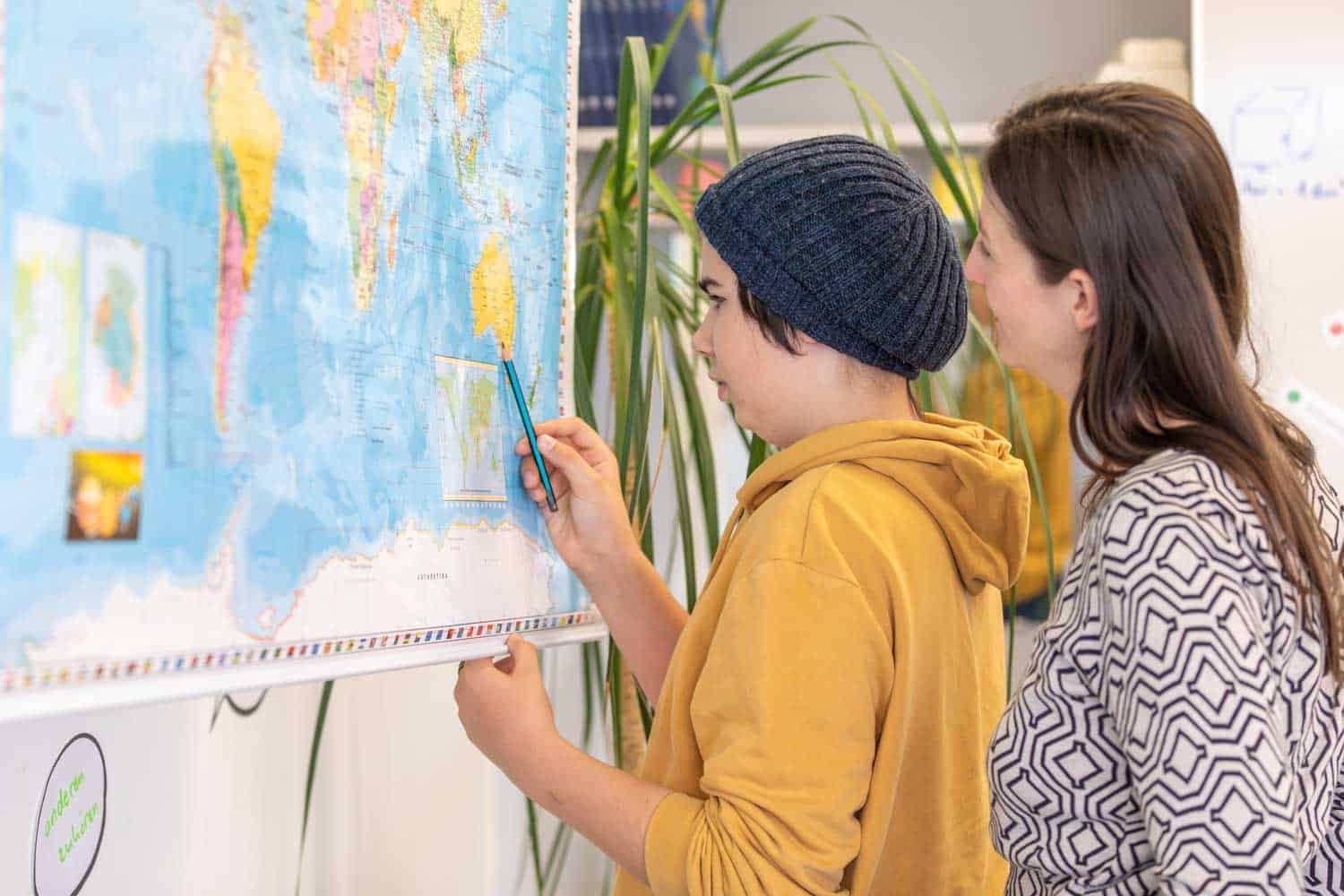 Junge erwachsene Frau studiert mit ihrer Betreuerin eine Weltkarte.