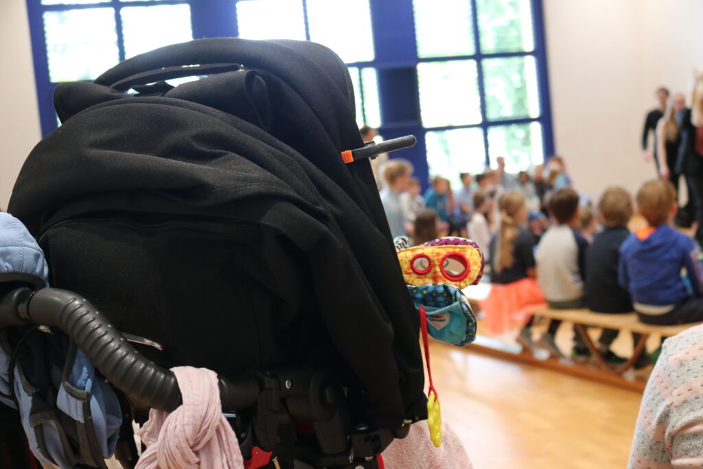 Bild von der Aufführung Musigkater Caruso. Rollstuhl und im Hintergrund Kindergartenkinder.